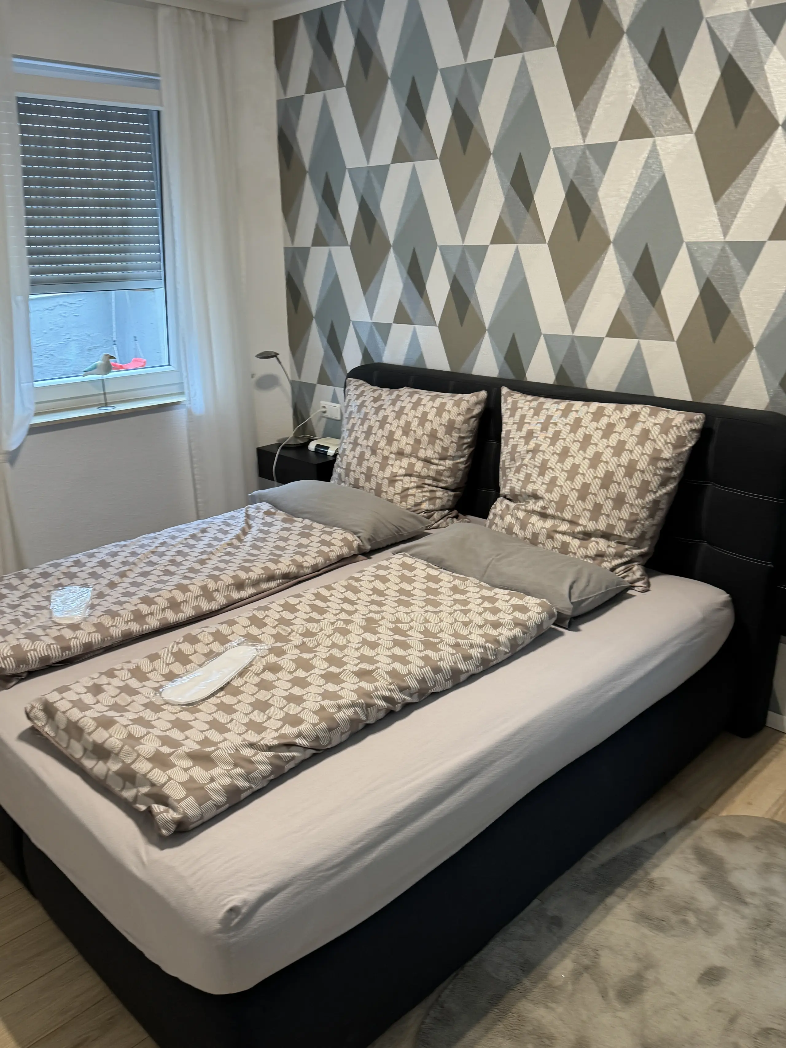 Schlafzimmer mit Doppelbett und Musterwand