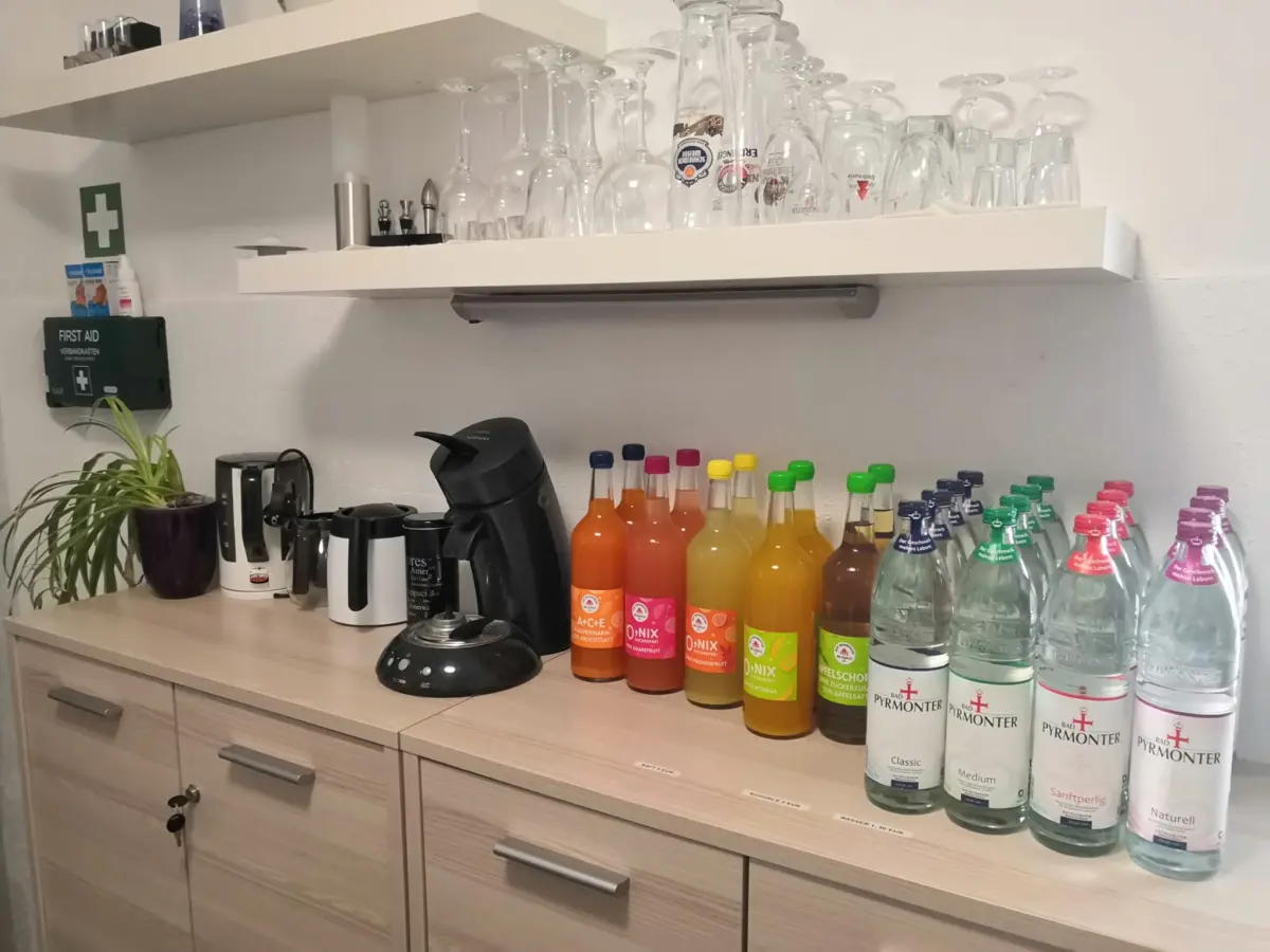 Regal mit Glaesern, Kaffeemaschine und Getraenken in der Gemeinschaftskueche