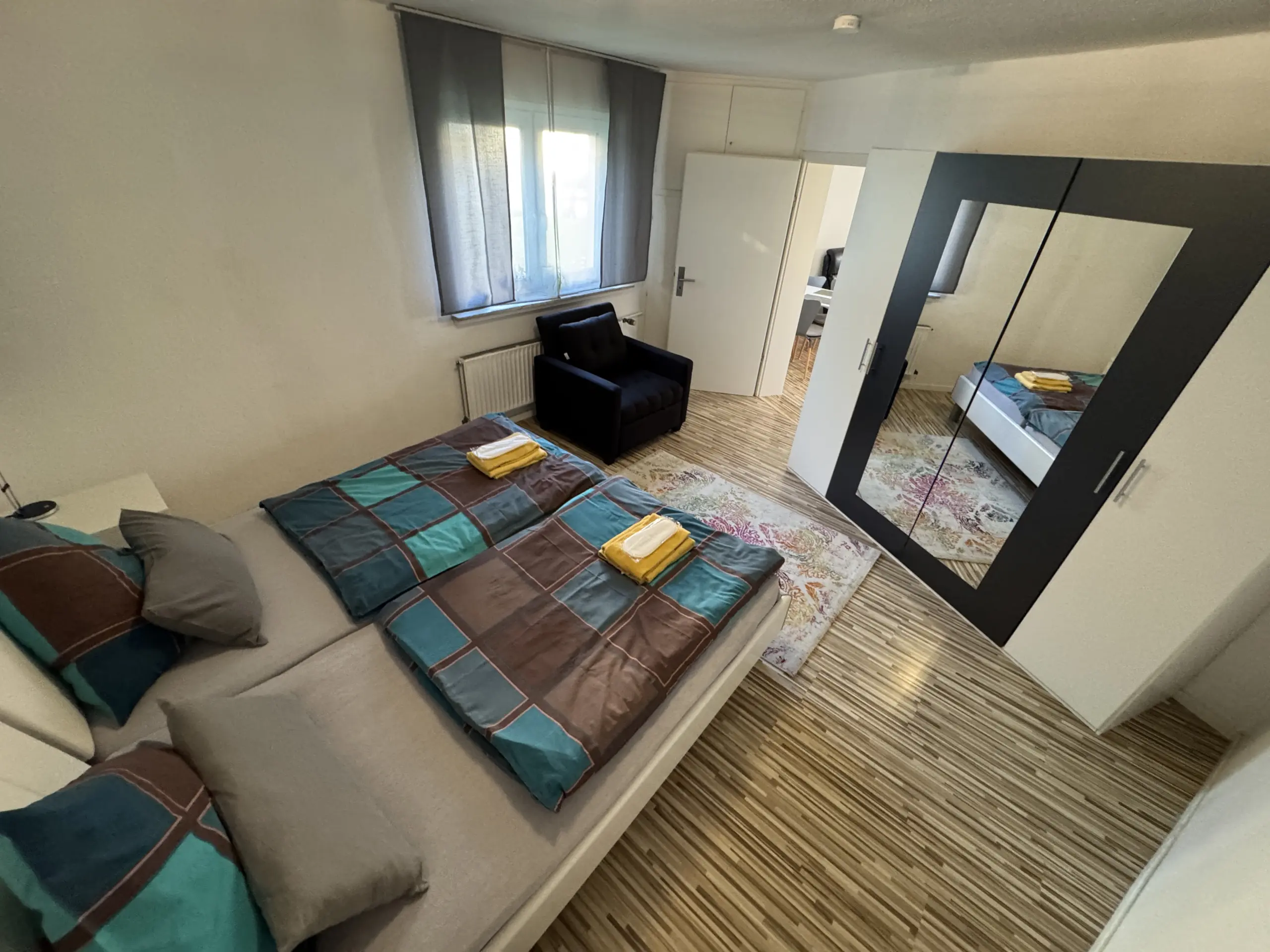 Schlafzimmer mit Spiegelschrank und Sessel